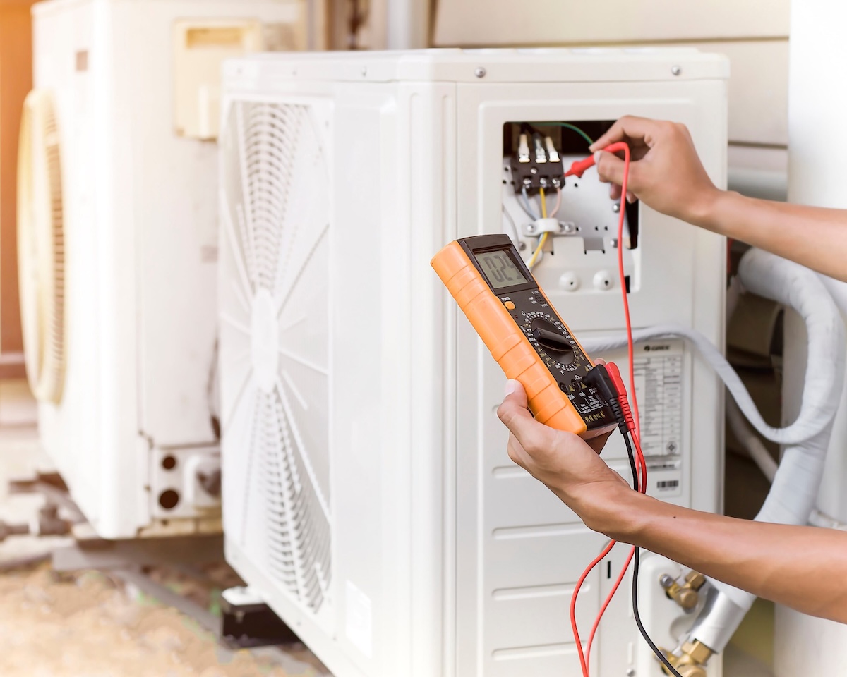 Technician testing a heat pump unit with a multimeter